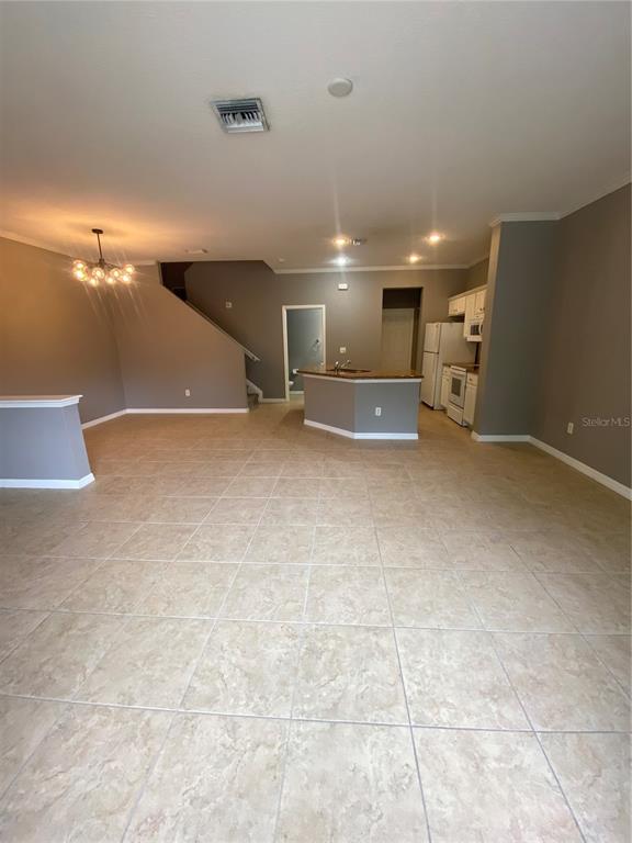 An open-concept living area features tile flooring, a kitchen island, and a staircase — 7441 ARLINGTON GROVE CIRCLE, TAMPA, FL