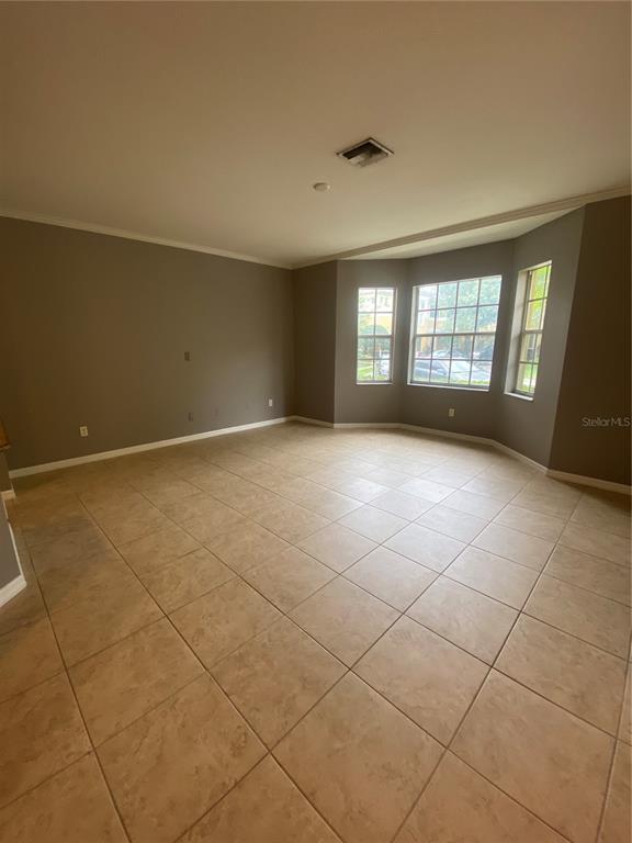 An empty room features beige tile flooring, gray walls, and a bay window — 7441 ARLINGTON GROVE CIRCLE, TAMPA, FL