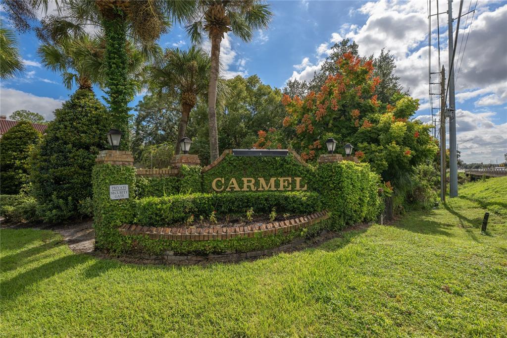A brick and ivy-covered monument sign for a community named Carmel sits in a yard — 1150 CARMEL CIRCLE UNIT 302, CASSELBERRY, FL