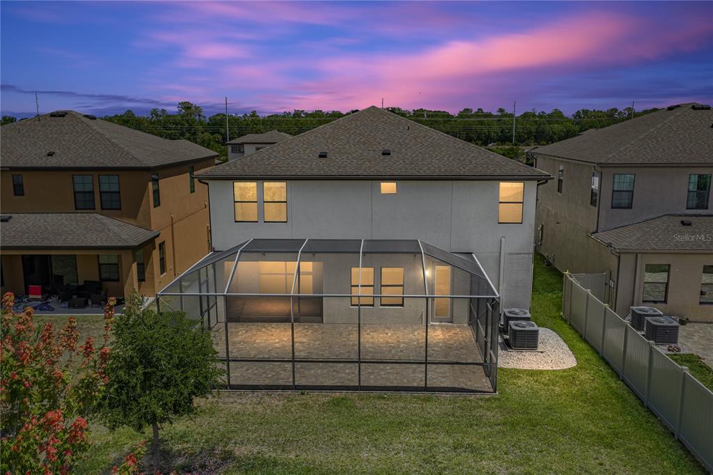 The rear exterior of a two-story house features a screened-in patio and a paved yard — 14633 RED CASTLE AVENUE, LITHIA, FL