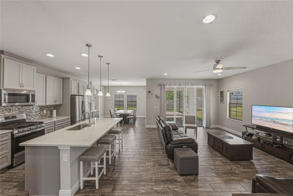 An open-concept kitchen and living area features light gray cabinetry, a large island, and tile flooring — 14633 RED CASTLE AVENUE, LITHIA, FL
