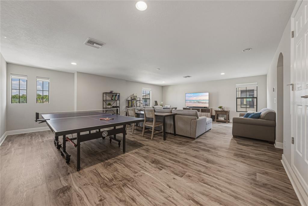 A spacious game room features wood-look flooring, a ping pong table, and a sectional sofa — 14633 RED CASTLE AVENUE, LITHIA, FL