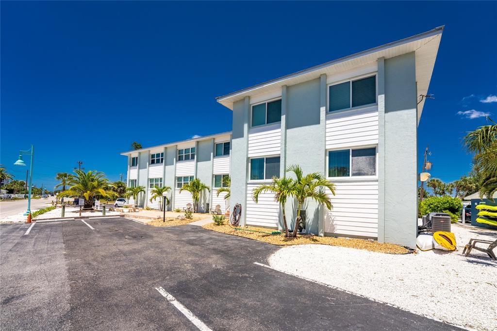 A two-story, light-colored apartment building stands next to a paved parking lot with palm trees — 1285 GULF BOULEVARD UNIT 4, ENGLEWOOD, FL