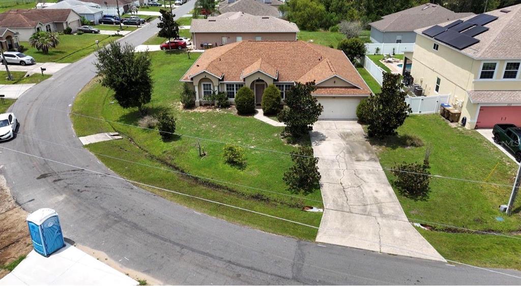 An aerial view of a single-story suburban house with a brown roof and concrete driveway — 1126 LAVAUR COURT, KISSIMMEE, FL
