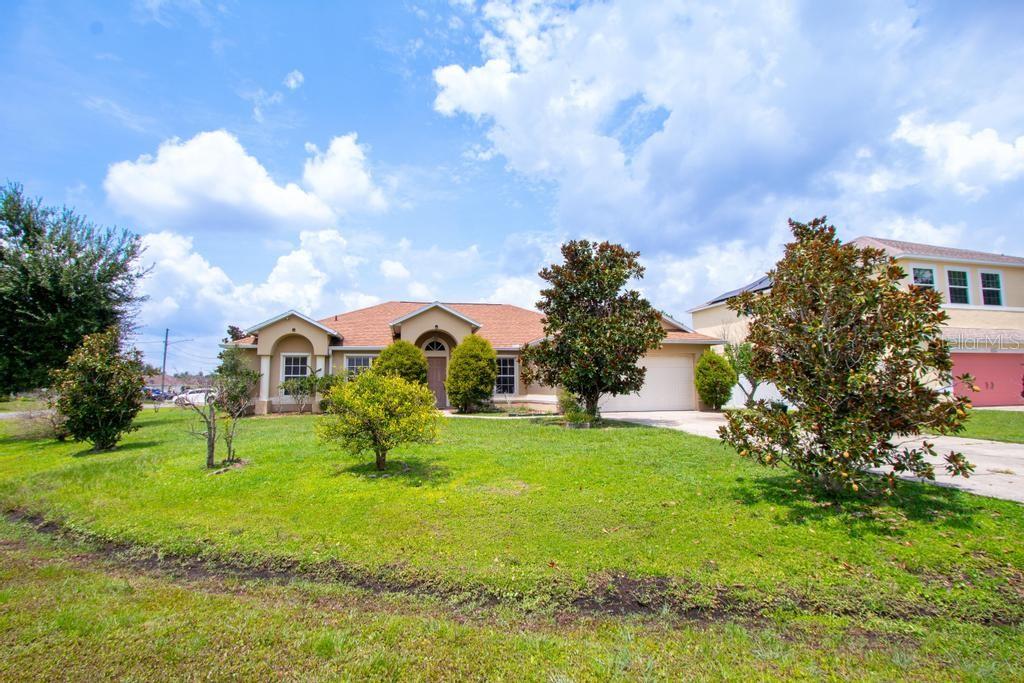 A single-story suburban house with a tan exterior, a two-car garage, and a grassy lawn — 1126 LAVAUR COURT, KISSIMMEE, FL