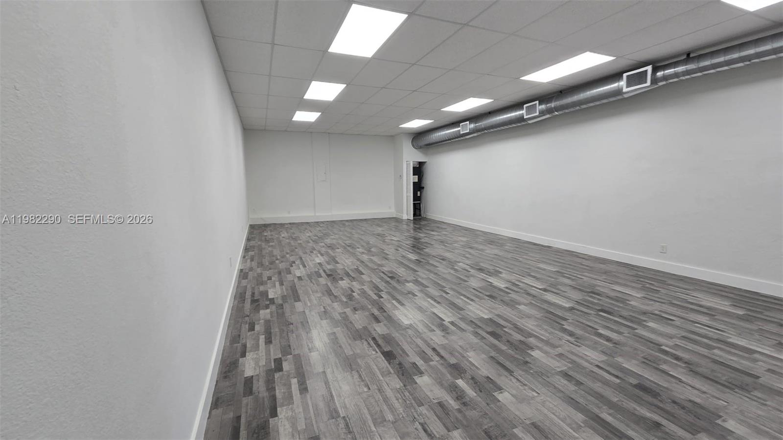 A vacant room features white walls, a gray wood-look floor, and exposed ceiling ductwork — 957 SW 122nd Ave # 957, Miami FL 33184, MIAMI, FL