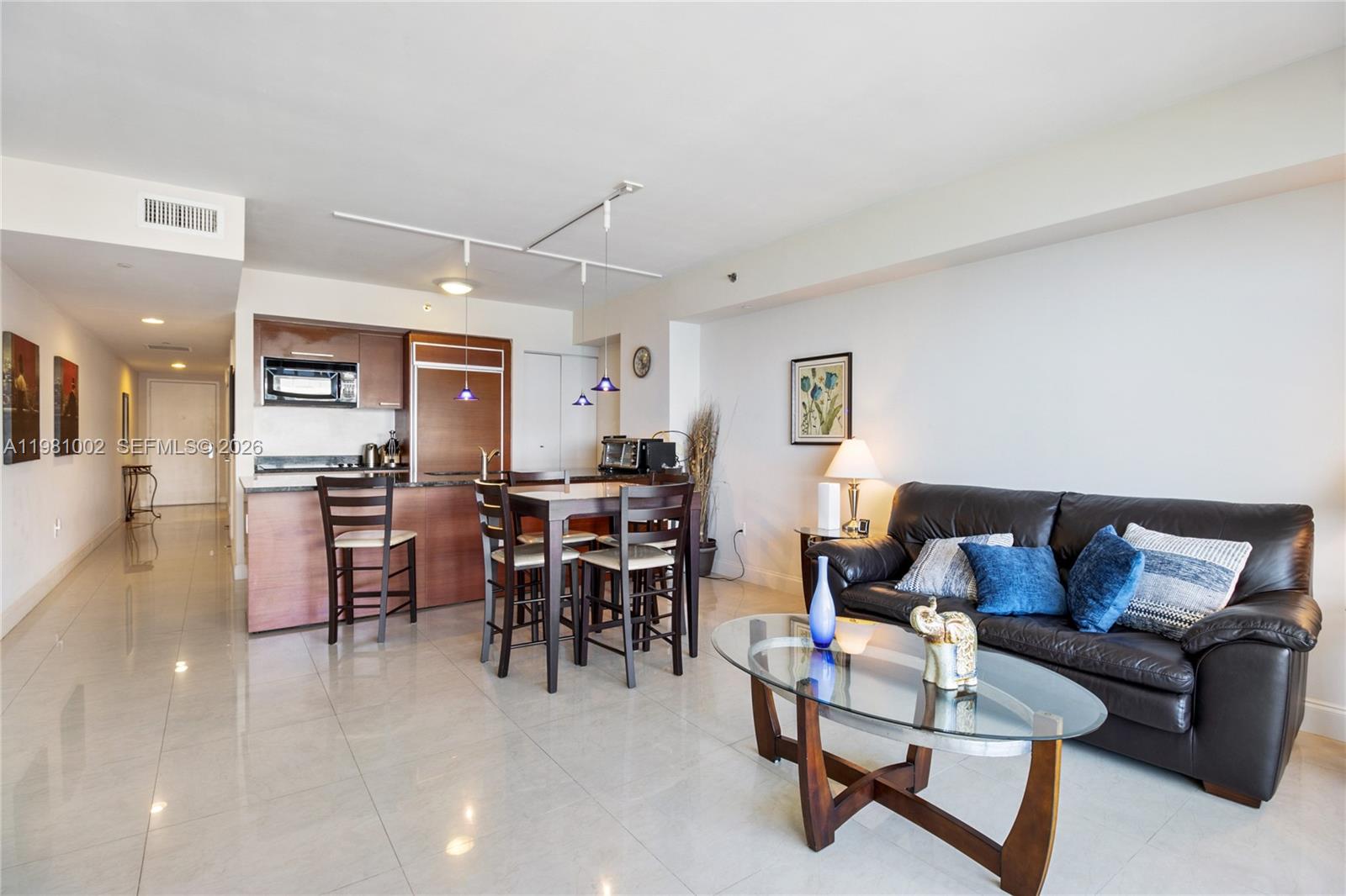 An open-concept living and dining area features tile floors, a dark leather sofa, and kitchen — 1830 S OCEAN DR # 4409, Hallandale Beach FL 33009, HALLANDALE BEACH, FL