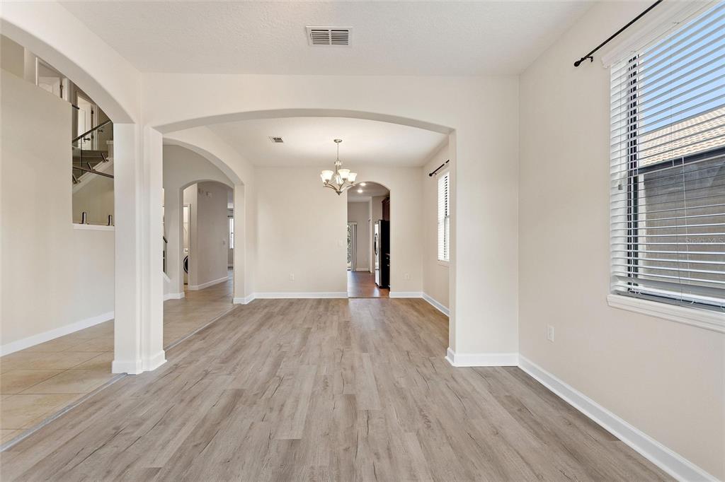 An interior view shows an open-concept dining area with light wood-look flooring and arched doorways — 1315 MOSS CREEK LN, DAVENPORT, FL