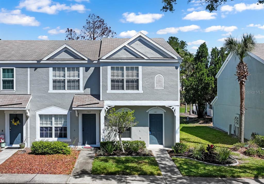 A two-story gray townhouse exterior features three front doors and a small front yard — 2411 LAKE WOODBERRY CIRCLE, BRANDON, FL
