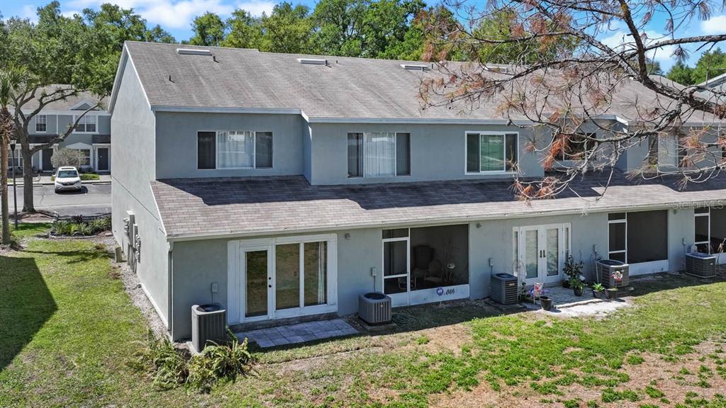An exterior view of a two-story townhouse with a screened patio and backyard — 2411 LAKE WOODBERRY CIRCLE, BRANDON, FL