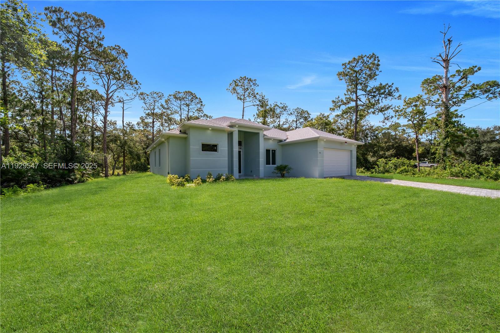A light green single-story house with a garage stands on a large grassy lot — 1912 Roosevelt, Lehigh Acres FL 33972, LEHIGH ACRES, FL