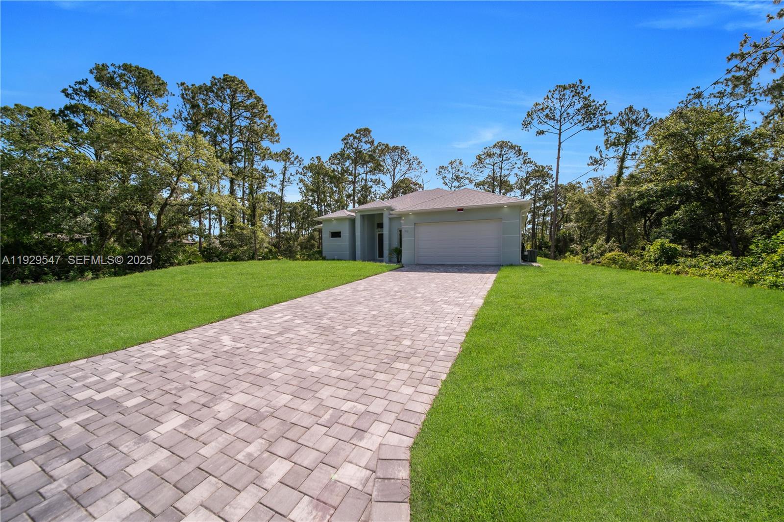A single-story house with a paved driveway and a two-car garage sits on a lawn — 1912 Roosevelt, Lehigh Acres FL 33972, LEHIGH ACRES, FL