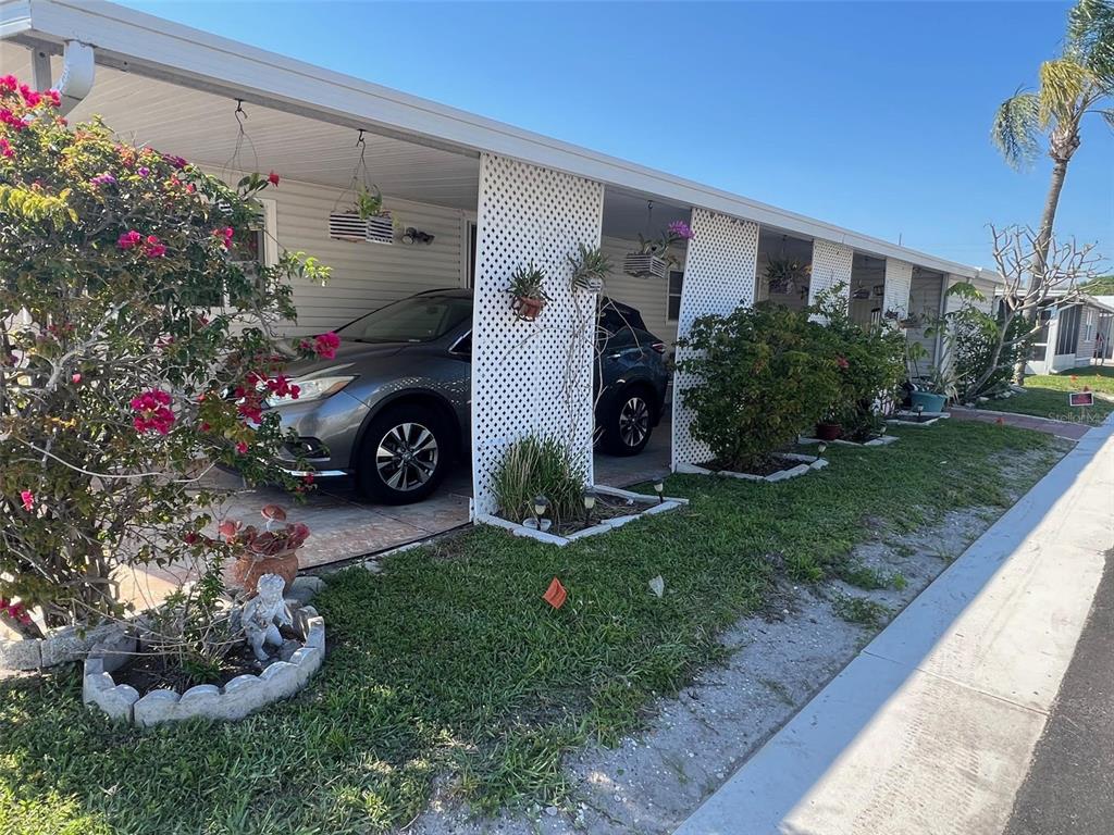 A gray SUV is parked under the carport of a mobile home with lattice screens — 11300 124TH AVENUE UNIT 95, LARGO, FL