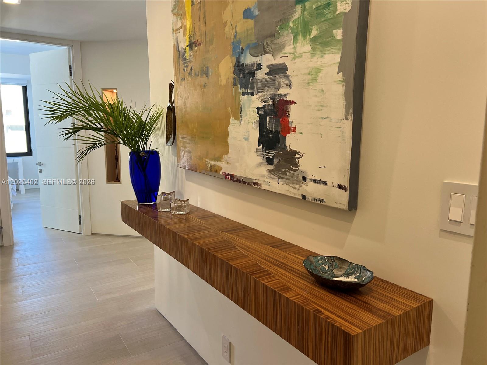 A hallway features a floating wood-grain console table, a large abstract painting, and a blue vase — 201 Crandon Blvd # 642, Key Biscayne FL 33149, KEY BISCAYNE, FL