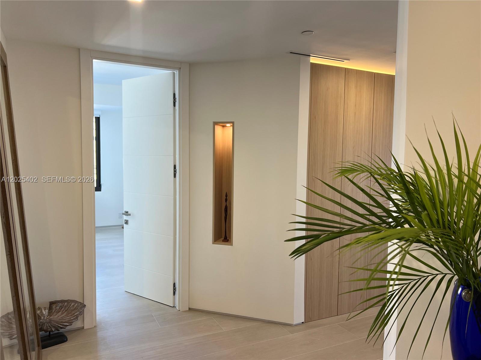 A hallway features a white door, a recessed wall niche, and wood-paneled cabinetry — 201 Crandon Blvd # 642, Key Biscayne FL 33149, KEY BISCAYNE, FL