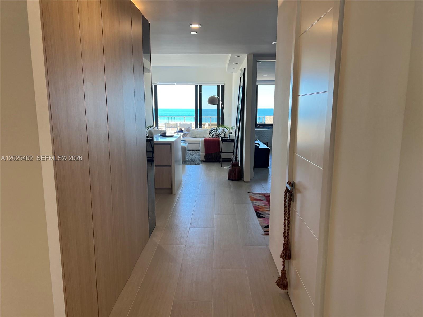 A hallway with wood-paneled walls leads to a living area with ocean views — 201 Crandon Blvd # 642, Key Biscayne FL 33149, KEY BISCAYNE, FL