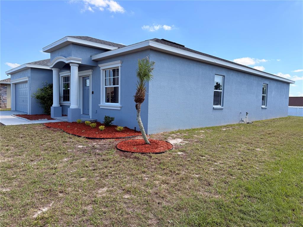 A blue single-story house with a front porch, columns, and a small palm tree — 1192 NORMANDY HEIGHTS CIRCLE, WINTER HAVEN, FL