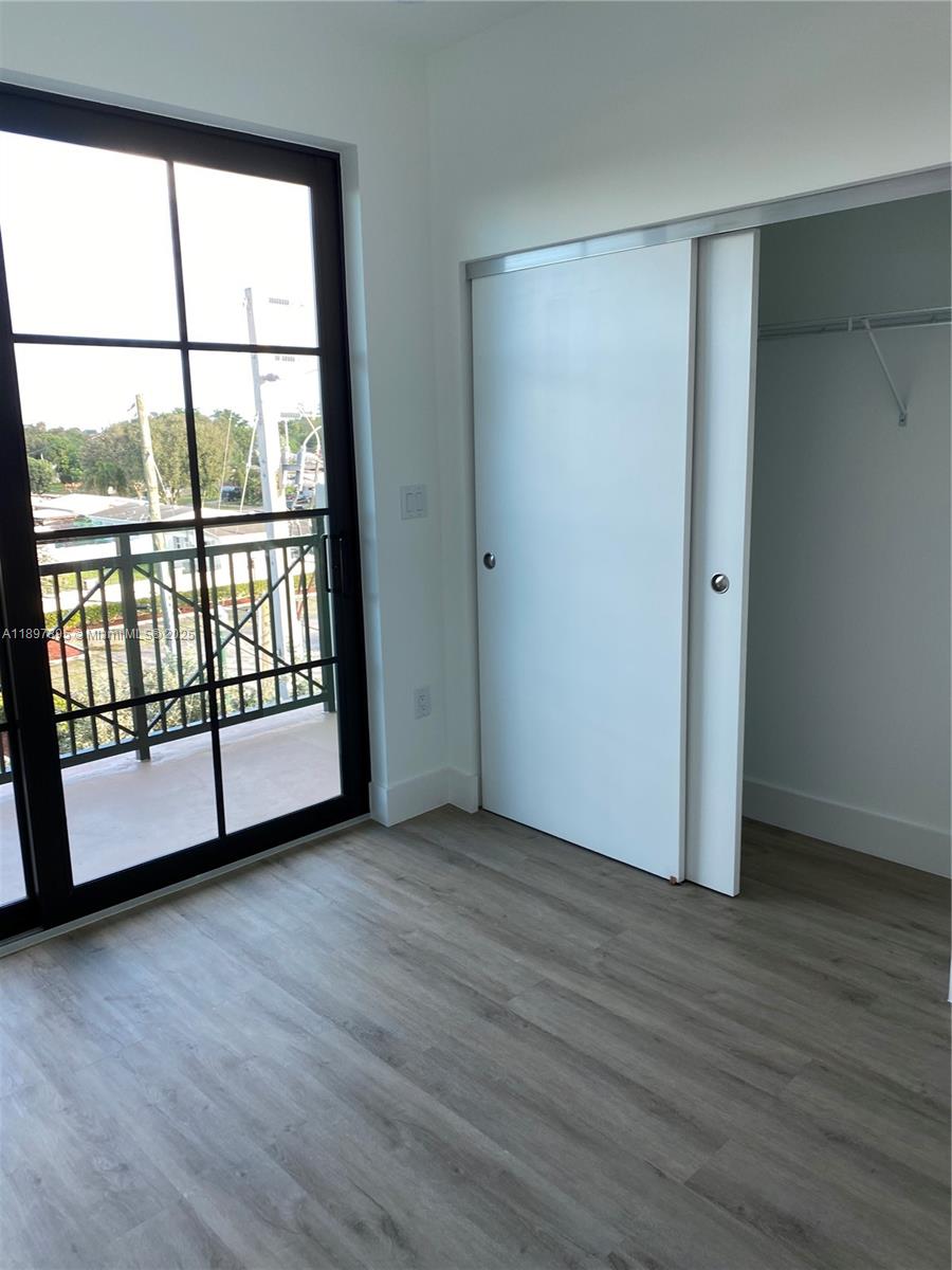 A room features light wood-look flooring, a sliding closet, and a large black-framed glass door — 4100 SW 64th Ave # 314, Davie FL 33314, DAVIE, FL