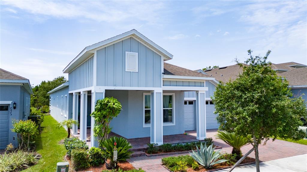 A light blue house with vertical siding, a covered porch, and a brick driveway — 7687 BOWERY DRIVE, WINTER GARDEN, FL