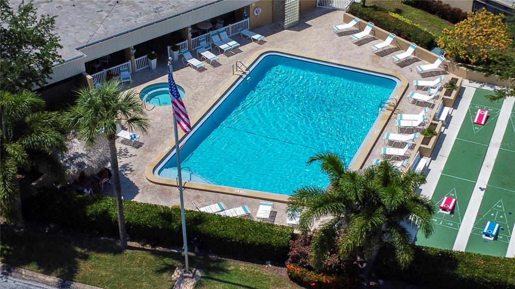 An aerial view shows a swimming pool, hot tub, lounge chairs, and shuffleboard courts — 2616 COVE CAY DRIVE UNIT 506, CLEARWATER, FL