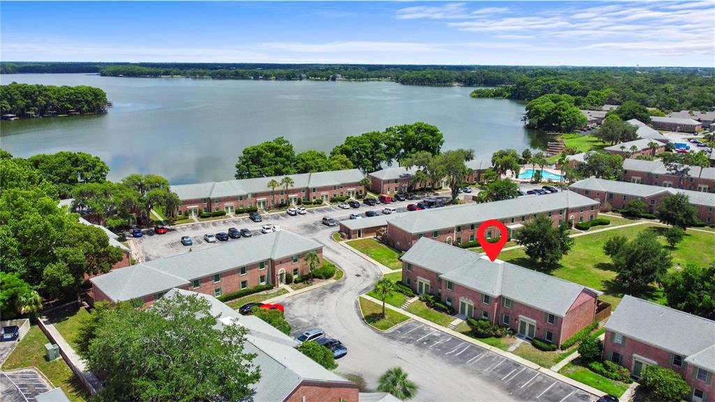 An aerial view shows brick apartment buildings near a lake with a red location marker — 116 GEORGETOWN DRIVE, CASSELBERRY, FL