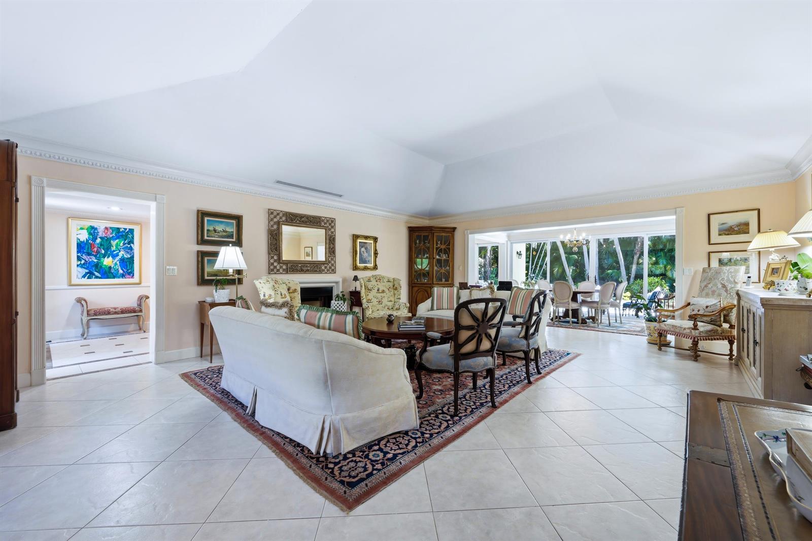 A spacious living room with tile floors, a vaulted ceiling, and a large area rug — 265 Fairview Road, Palm Beach FL 33480, PALM BEACH, FL