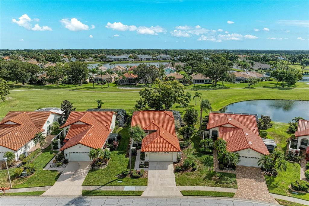 An aerial view shows three houses with orange tile roofs and screened-in pool enclosures — 4909 CLUBVIEW COURT E, BRADENTON, FL