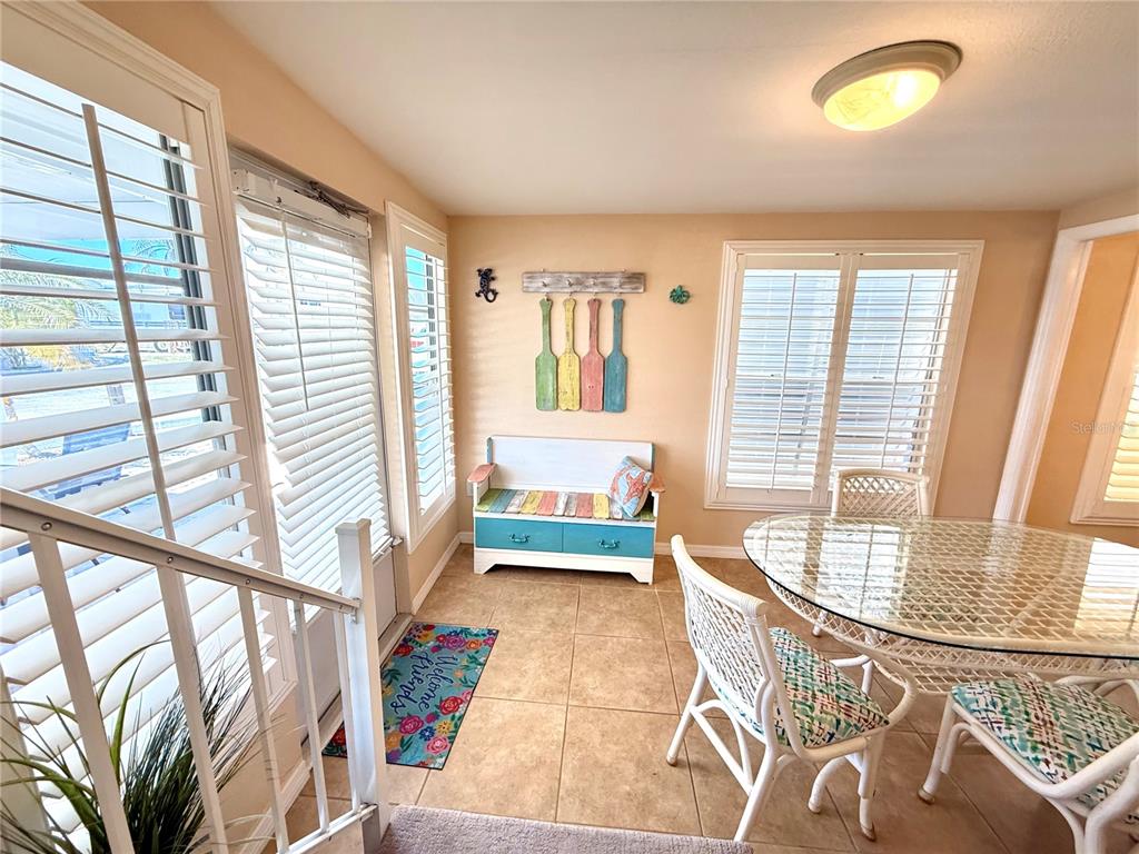 A sunroom features tile flooring, a dining set, a bench, and windows with white shutters — 1475 FLAMINGO DRIVE UNIT 128, ENGLEWOOD, FL