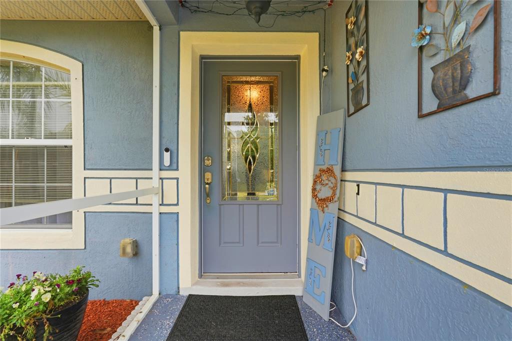 A blue front door with a decorative glass insert sits on a covered porch — 1909 CONCH LANE, KISSIMMEE, FL