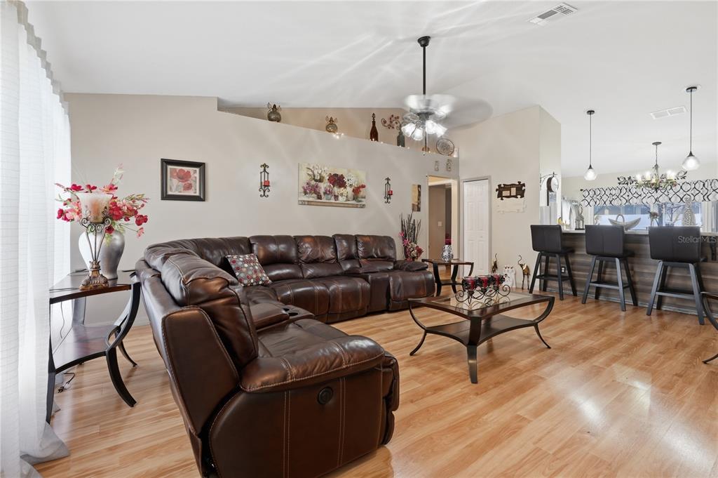 A living room features a large brown leather sectional, wood flooring, and a kitchen breakfast bar — 1909 CONCH LANE, KISSIMMEE, FL