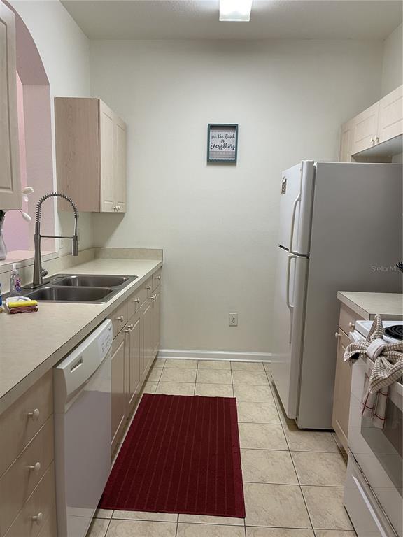 A kitchen features light-colored cabinets, a white dishwasher, a refrigerator, and a double sink — 2306 SILVER PALM DRIVE UNIT 105, KISSIMMEE, FL