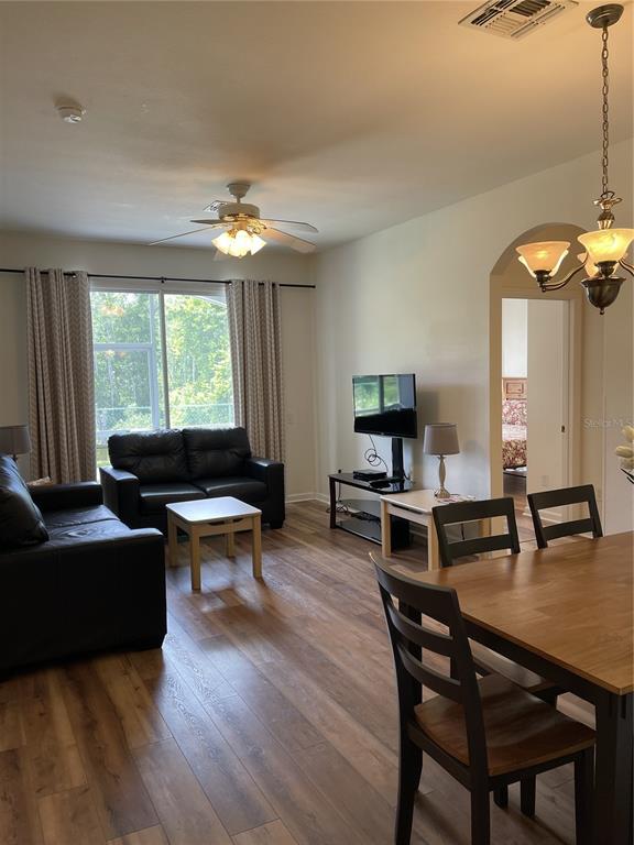 A living room and dining area feature wood-look flooring, a ceiling fan, and black furniture — 2306 SILVER PALM DRIVE UNIT 105, KISSIMMEE, FL