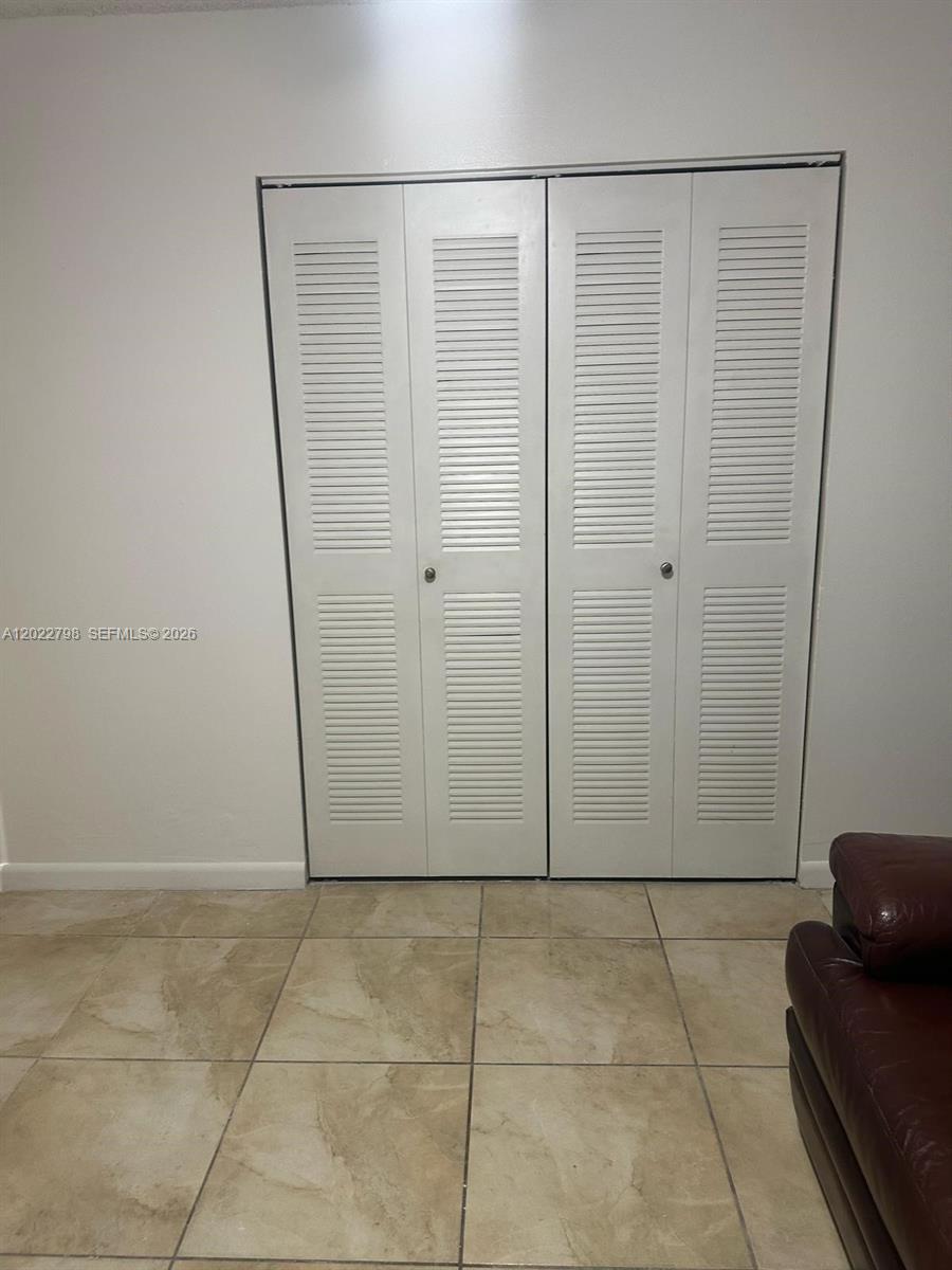 A room features white louvered bifold closet doors and light-colored tile flooring — 1115 SW 136th Pl # 2, Miami FL 33184, MIAMI, FL