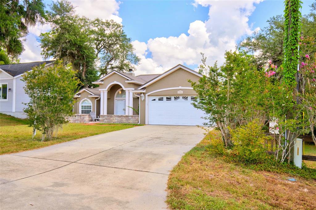 An aerial view shows a tan house with a metal roof, deck, and private wooden dock — 13059 NE 7TH LOOP, SILVER SPRINGS, FL