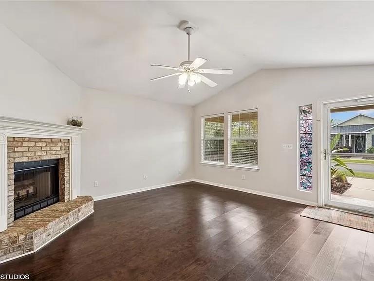 A bedroom features a gray upholstered bed, dark wood floors, and a white ceiling fan — 3775 NW 26TH STREET, GAINESVILLE, FL