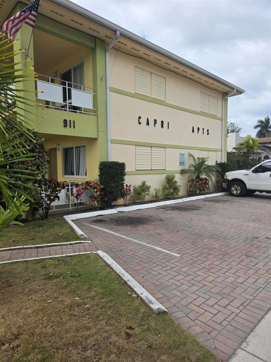 A three-story apartment building with a brick parking lot and a green-trimmed exterior — 911 N Federal Highway # 106, FL 33460, FL