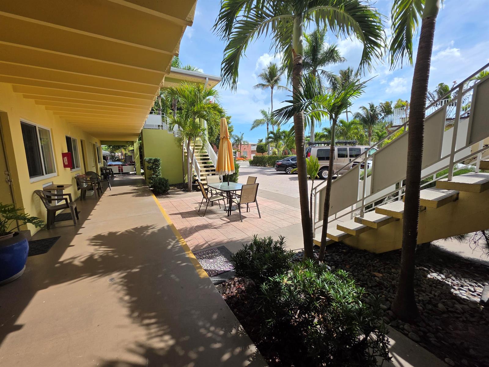 A yellow building exterior features a covered walkway, outdoor seating, and a staircase — 911 N Federal Highway # 106, FL 33460, FL