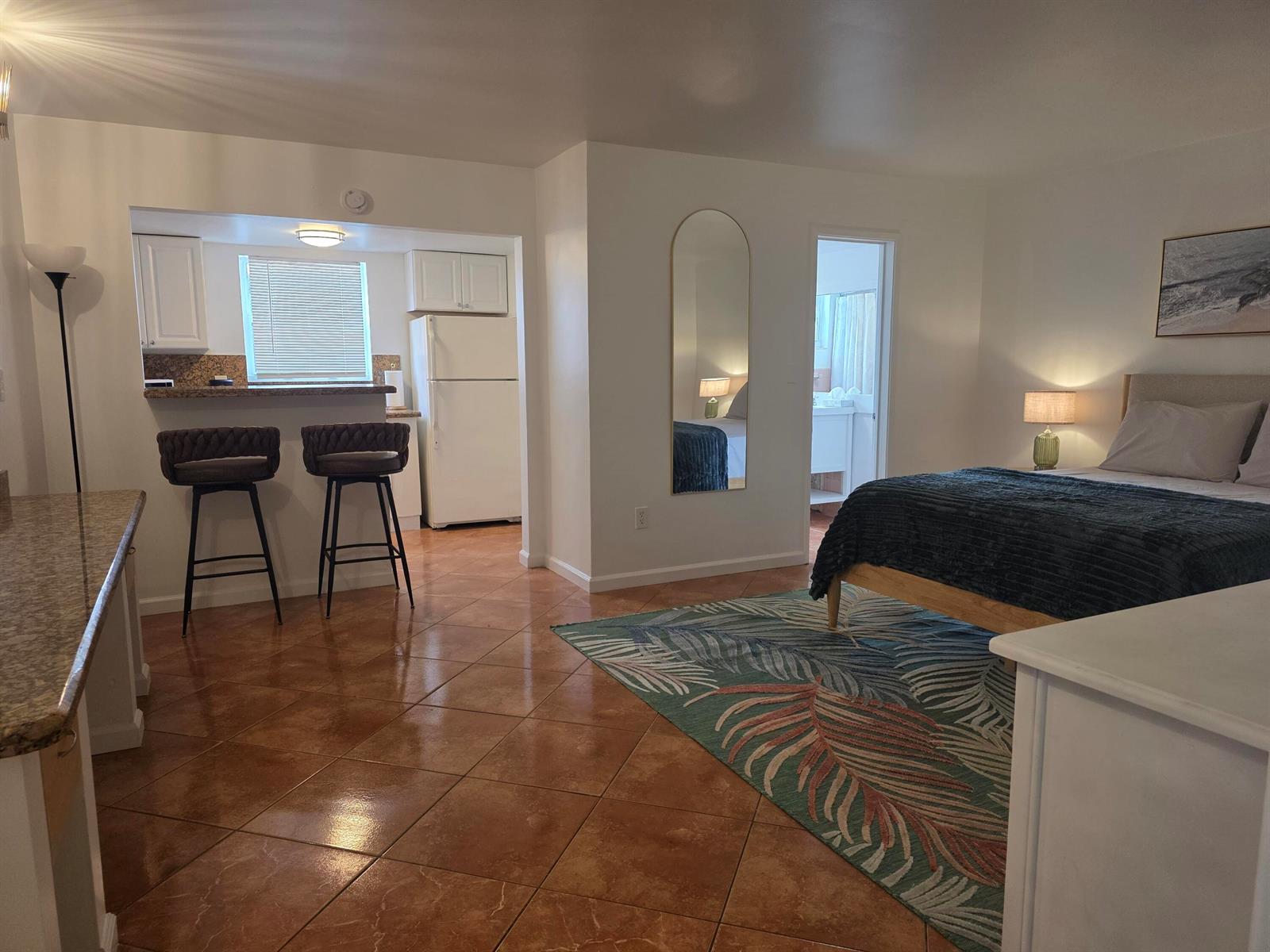 A studio apartment features a kitchen with a breakfast bar, tiled floors, and a bed — 911 N Federal Highway # 106, FL 33460, FL