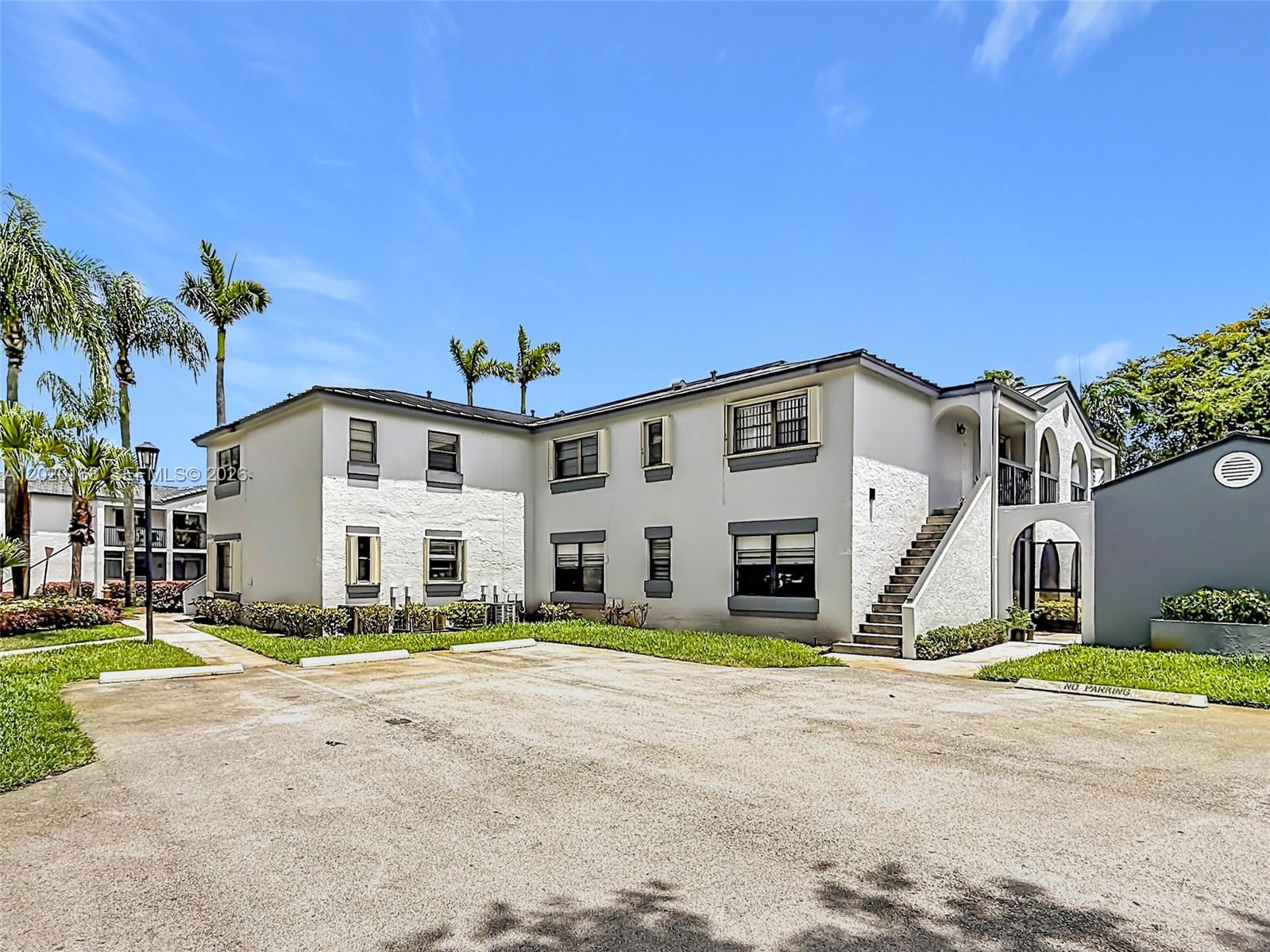 A two-story apartment building with white stucco walls, dark trim, and an exterior staircase — 18296 Mediterranean Blvd # 404, Hialeah FL 33015, HIALEAH, FL