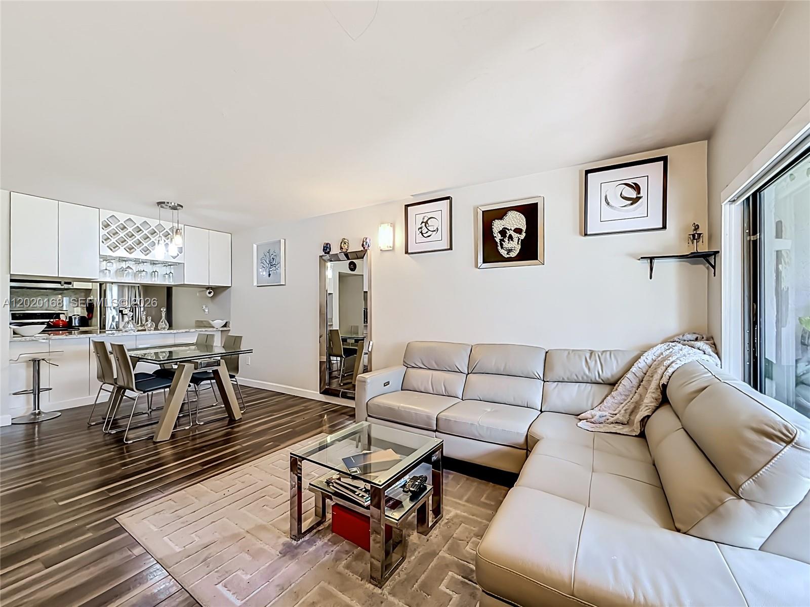 A living room and dining area feature a sectional sofa, glass table, and wood flooring — 18296 Mediterranean Blvd # 404, Hialeah FL 33015, HIALEAH, FL