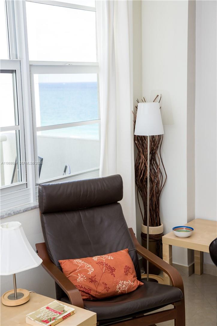 A dark leather armchair with an orange pillow sits beside a window overlooking the ocean — 3725 S Ocean Dr # 1003, Hollywood FL 33019, HOLLYWOOD, FL
