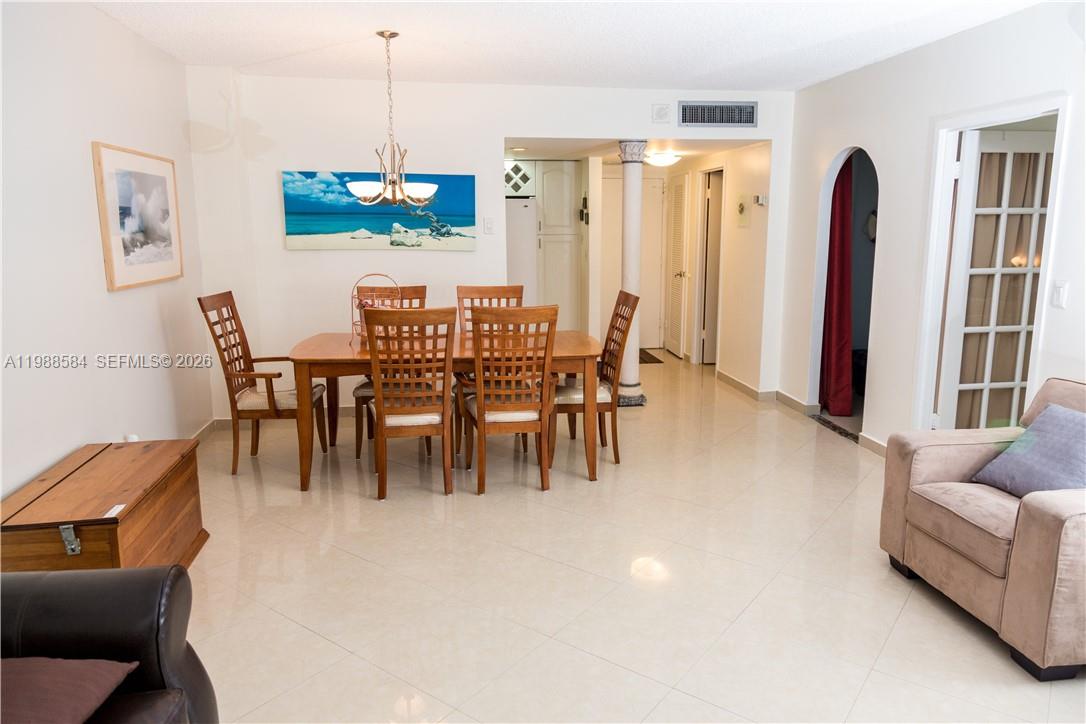 A dining area with a wooden table and chairs sits adjacent to a living space — 3725 S Ocean Dr # 1003, Hollywood FL 33019, HOLLYWOOD, FL