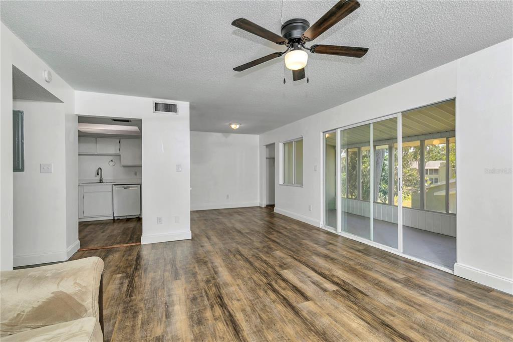 A living room with wood-look flooring, a ceiling fan, and sliding glass doors to a porch — 637 SILVER PASS UNIT B, OCALA, FL