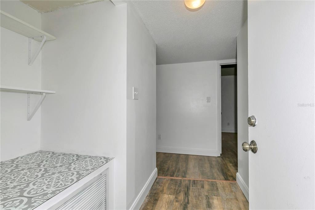 A hallway with wood-look flooring, white walls, open shelving, and a patterned tiled surface — 637 SILVER PASS UNIT B, OCALA, FL
