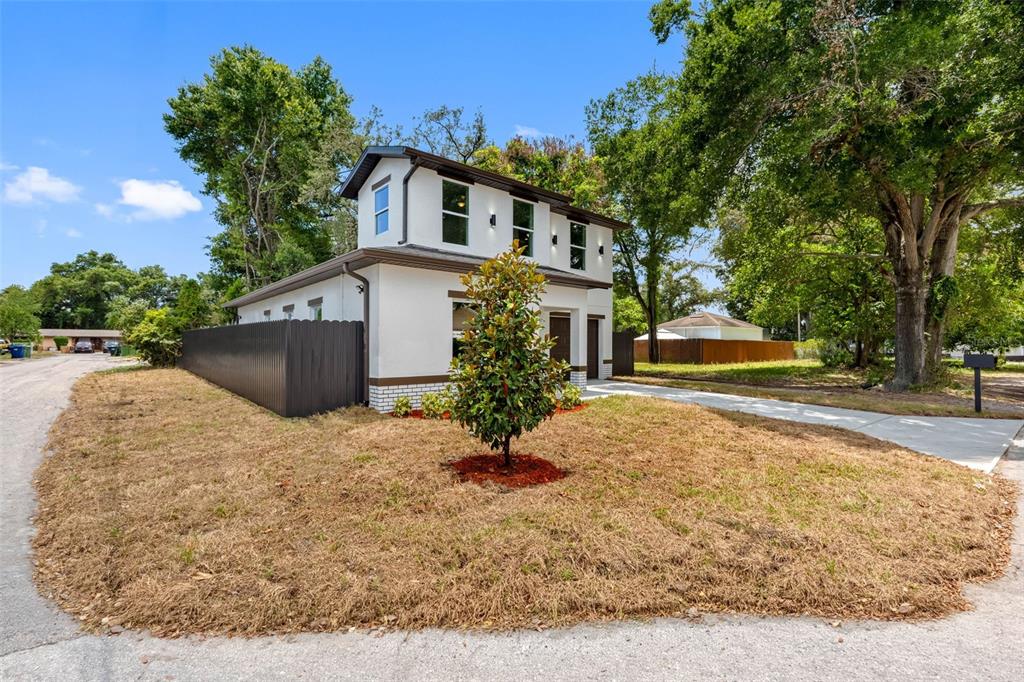A two-story white house with a brown roof and fence sits on a grassy lot — 2405 E 23RD AVENUE, TAMPA, FL