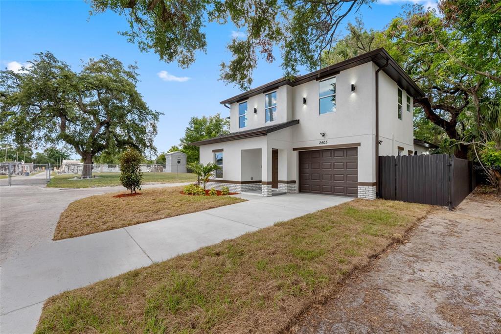 A two-story house with a white stucco exterior, brown garage door, and a concrete driveway — 2405 E 23RD AVENUE, TAMPA, FL