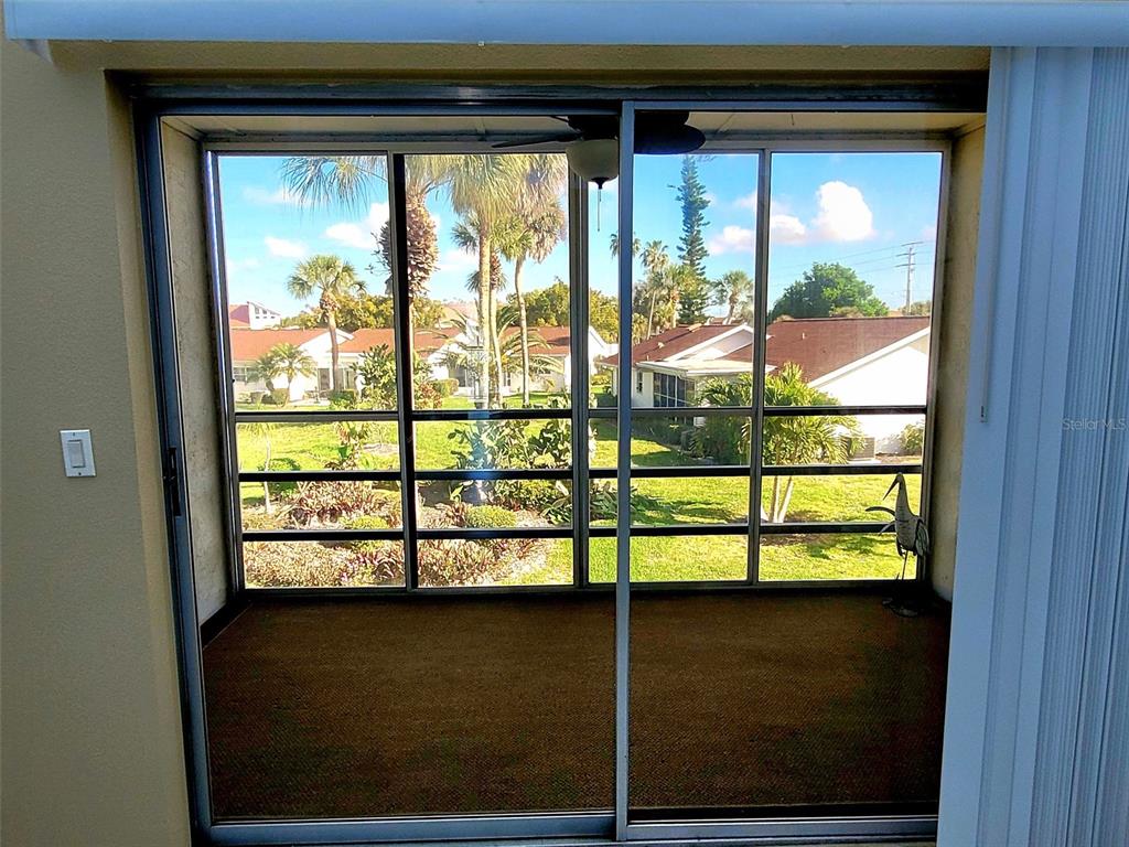A carpeted enclosed porch features large sliding glass doors looking out onto a grassy yard — 729 CAPRI ISLES BOULEVARD UNIT 216, VENICE, FL