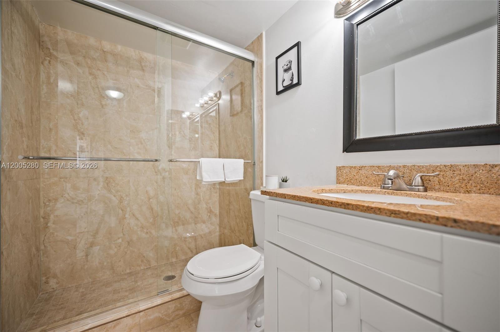A bathroom features a glass-enclosed tiled shower, a white vanity, and a granite countertop — 7195 NW 179th St # 106, Hialeah FL 33015, HIALEAH, FL