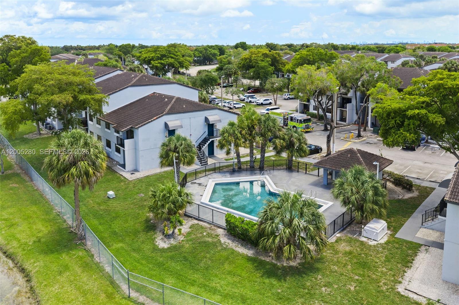 An aerial view shows an apartment complex with a swimming pool, palm trees, and parking — 7195 NW 179th St # 106, Hialeah FL 33015, HIALEAH, FL