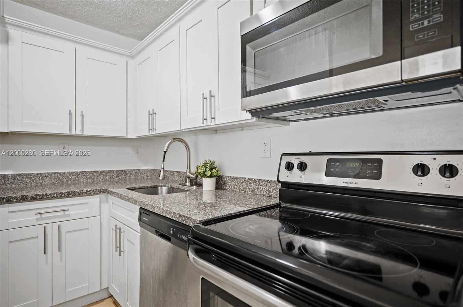 A kitchen features white cabinets, granite countertops, stainless steel appliances, and a black electric stove — 7195 NW 179th St # 106, Hialeah FL 33015, HIALEAH, FL